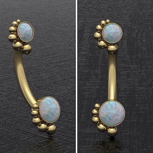 Puede incluir: Joyería corporal de oro con un grupo de pequeñas bolas doradas en cada extremo y una piedra de ópalo redonda en el centro de cada grupo.