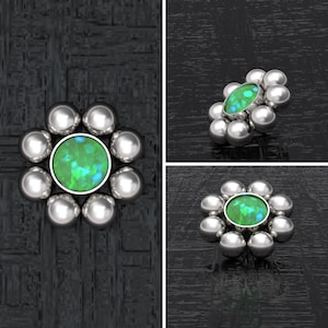 May include: A silver flower-shaped body jewelry piece with a green opal gemstone in the center. The piece is made up of eight small silver balls surrounding the gemstone.