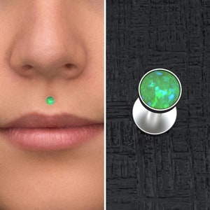 Peut inclure: Un piercing de lèvre inférieure en forme de clou avec une opale verte et une base argentée.