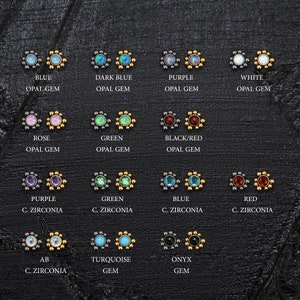 May include: A variety of opal and cubic zirconia gems in different colors, set in gold and silver, with a flower-shaped design. The gems are displayed on a black background.