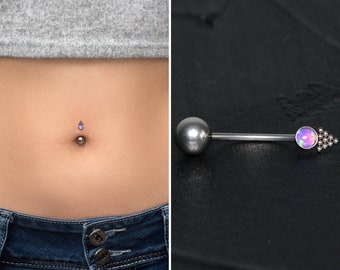 Peut inclure: Un piercing de nombril argenté doté d'une pierre d'opale ronde aux reflets violets sertie dans une monture en métal. L'embout décoratif présente un petit groupe triangulaire de minuscules sphères métalliques à la base.