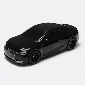 May include: A black coupe car model with black wheels. The miniature vehicle has a detailed front grille and headlights. The car is a sleek, modern design, likely a collectible or toy.