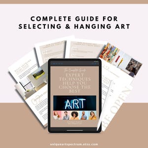 Peut inclure: Une tablette numérique affichant "The Complete Guide" avec des techniques d'experts pour choisir de l'art. Autour de la tablette, des guides imprimés avec du texte comme "How to Hang Art Correctly" et "What Artwork Grabs Your Attention". L'image est sur un fond neutre.