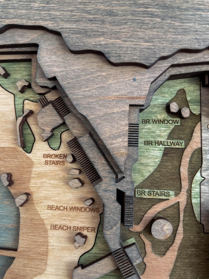 May include: A multi-layered wooden map with various sections labeled. The map features text labels such as "BROKEN STAIRS", "BEACH WINDOWS", and "BR STAIRS". The color palette includes shades of brown, green, and gray.