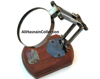 May include: Antique brass magnifying glass with a wooden base and a brass plaque that reads "Weston & Son Opticians London 1825".