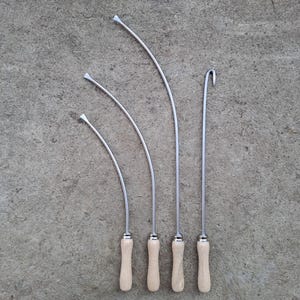 May include: Four metal tools with wooden handles. The tools are curved and have a pointed tip. The tools are arranged in order of size, with the largest tool on the left and the smallest tool on the right.