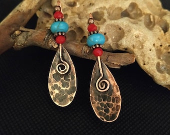 May include: A pair of copper dangle earrings with turquoise and red beads. The earrings feature a hammered copper teardrop shape with a wire swirl detail.