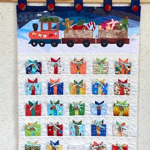 Puede incluir: Calendario de Adviento navideño hecho a mano con un tren que transporta regalos y una serie de pequeñas cajas de regalo cubiertas de tela. El tren es rojo, naranja y verde, con un hombre de jengibre y bastones de caramelo en la carga. Las cajas de regalo son de varios colores y patrones.