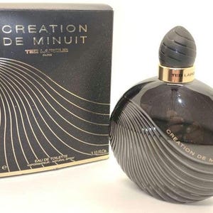 Könnte beinhalten: Ein schwarzes und goldenes Flakon des Parfüms Creation de Minuit von Ted Lapidus. Das Flakon ist 100 ml groß und hat die Form einer Welle. Die Schachtel ist schwarz mit goldenen Schriftzügen und einem Wellenmuster.