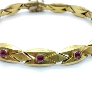 Peut inclure: Un bracelet en or avec un motif géométrique et trois pierres précieuses roses.