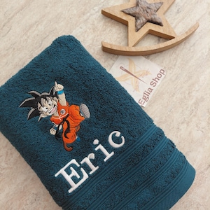 Può includere: Un asciugamano da bagno color verde acqua scuro con il ricamo di un personaggio dei cartoni animati dai capelli a punta in uniforme da arti marziali arancione, il nome Eric ricamato in bianco e una stella decorativa in legno.