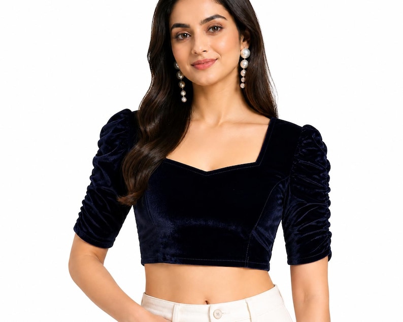 May include: A dark navy blue velvet crop top featuring a square neckline and elbow-length sleeves with gathered, ruched detailing. The fitted bodice is constructed from a soft, plush fabric, providing a structured silhouette with a clean, straight hemline.