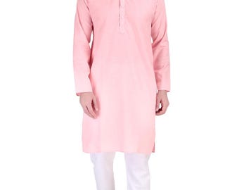 Puede incluir: Una persona vestida con un kurta rosa claro con cuello mandarín y tapeta abotonada, combinado con pantalones blancos. El atuendo se completa con sandalias marrones. La ropa es probablemente de algodón.