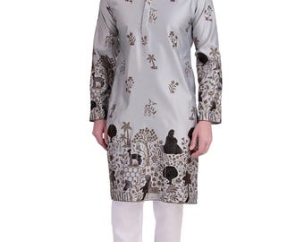 Puede incluir: Una túnica gris claro con cuello mandarín y mangas largas, adornada con un estampado floral y natural en marrón. La túnica se combina con pantalones blancos y zapatos marrones, creando un conjunto coordinado.