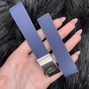 May include: Two blue watch bands with a silver buckle. The buckle has the word "LONGINES" engraved on it.