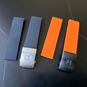May include: Four watch straps in the image. Two are black with silver clasps, and two are bright orange with black clasps. The clasps have a square logo. The straps are made of a flexible material.