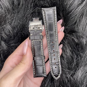 May include: Two black leather watch straps with white stitching. One strap has a metal buckle.