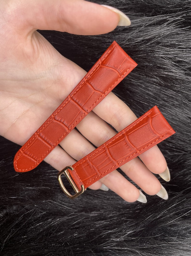 Puede incluir: Dos correas de reloj de cuero rojo con un patr&oacute;n de cocodrilo. Una correa tiene una hebilla dorada.