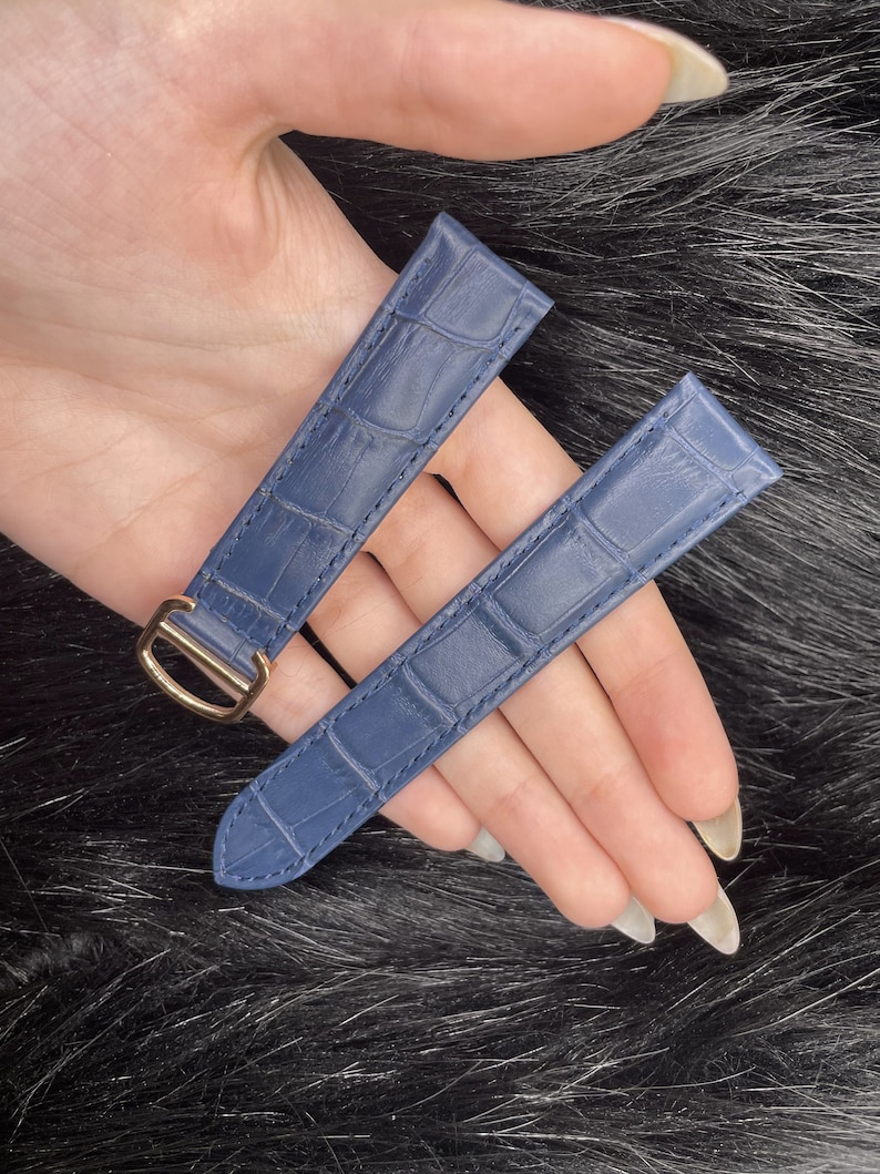 Puede incluir: Dos correas de reloj de cuero azul con estampado de cocodrilo. Una correa tiene una hebilla dorada.