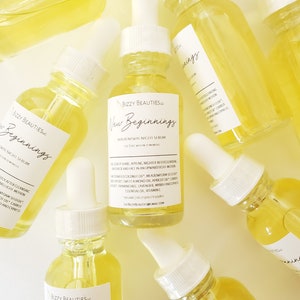 May include: Multiple glass bottles of yellow serum with white dropper tops and labels that read "Bizzy Beauties, Inc. New Beginnings Skin Renewal Night Serum See Results Within 12 Months".