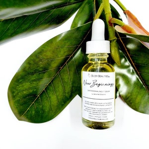 May include: A clear glass bottle with a white dropper top filled with a yellow liquid. The bottle is labeled "Bizzy Beauties" and "New Beginnings Skin Renewal Night Serum". The bottle is surrounded by green leaves.