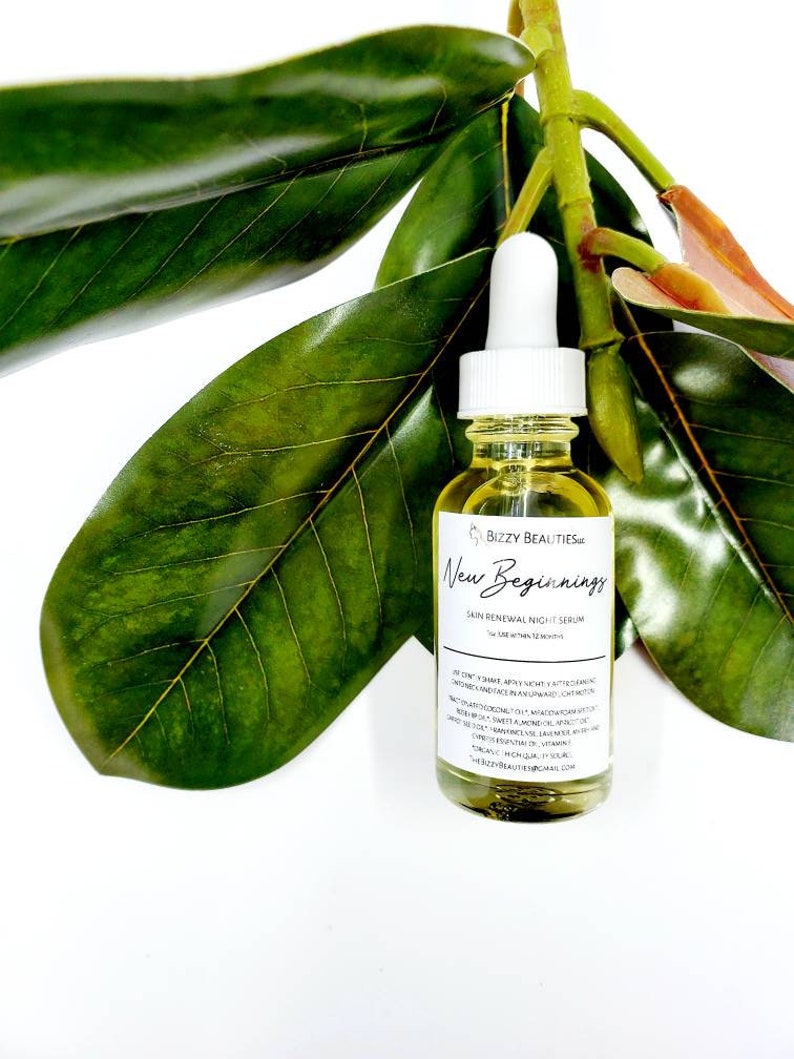 May include: A clear glass bottle with a white dropper top filled with a yellow liquid. The bottle is labeled "Bizzy Beauties" and "New Beginnings Skin Renewal Night Serum". The bottle is surrounded by green leaves.