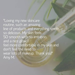 May include: A close-up of a clear glass bottle with a dropper, filled with a golden liquid. The bottle is surrounded by green leaves. The text "Loving my new skincare routine, such an amazing line of products and everything smells so delicious. My skin feels SO smooth with no irritation and a nice glow. I feel more comfortable in my skin and don't feel the need to wear lots of makeup. Thank you!" Amy M. is visible on the image.