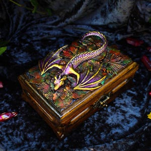 May include: A wooden box with a dragon design. The dragon is made of resin and is painted in shades of purple, gold, and green. The box is decorated with a variety of autumn leaves.