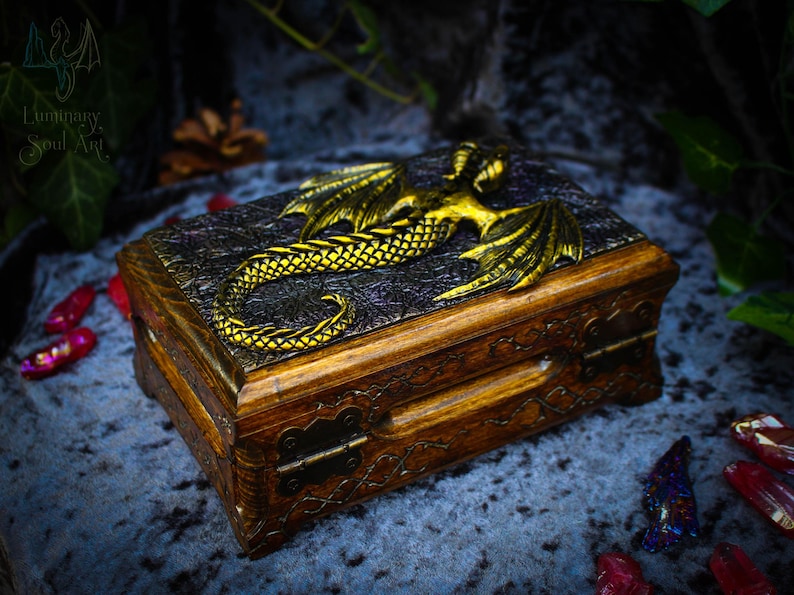 May include: A wooden box with a dragon design on the lid. The dragon is gold and has intricate details. The box has a hinged lid and a brass latch.