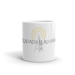 Puede incluir: Taza de cerámica blanca con un gráfico de torre de radio gris y amarillo y el texto "All Roads Lead Here".