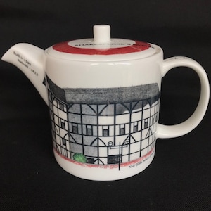 May include: White ceramic teapot with a red lid and a black and white image of Shakespeare's Globe Theatre. The text on the lid reads "Shakespeare's Globe" and the text on the side reads "Built in 1599,  Rebuilt - 1997".