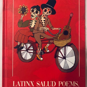 Peut inclure: Une couverture de livre rouge avec une illustration color&eacute;e de deux squelettes &agrave; v&eacute;lo. Les squelettes portent des chapeaux et l'un d'eux tient un tambourin. Le titre du livre est "Latinx Salud Poems, An Inaugural Collection".