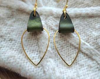 May include: A pair of gold hoop earrings with a green leather accent. The hoops are shaped like a teardrop and the leather is a dark green color.