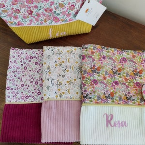 May include: Three floral fabric pouches with yellow, pink, and white corduroy bottoms. The pouches are personalized with the names "L&eacute;a", "Rosa", and a third name that is not visible in the image.