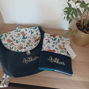 May include: A dark blue backpack and a matching book bag with a jungle animal print and the name "Arthur" embroidered on each.