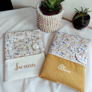 May include: Two personalized baby bibs with floral fabric and a corduroy bottom. The bibs are embroidered with the names "Alice" and "Swann".