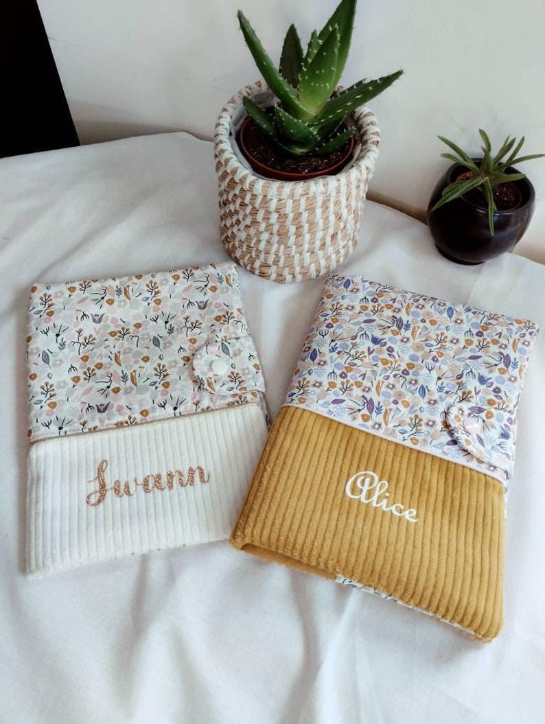 May include: Two personalized baby bibs with floral fabric and a corduroy bottom. The bibs are embroidered with the names "Alice" and "Swann".