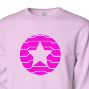 Puede incluir: Sudadera rosa claro con un dise&ntilde;o de estrella rosa brillante dentro de un patr&oacute;n circular. La estrella es blanca. La sudadera tiene mangas largas y cuello redondo.