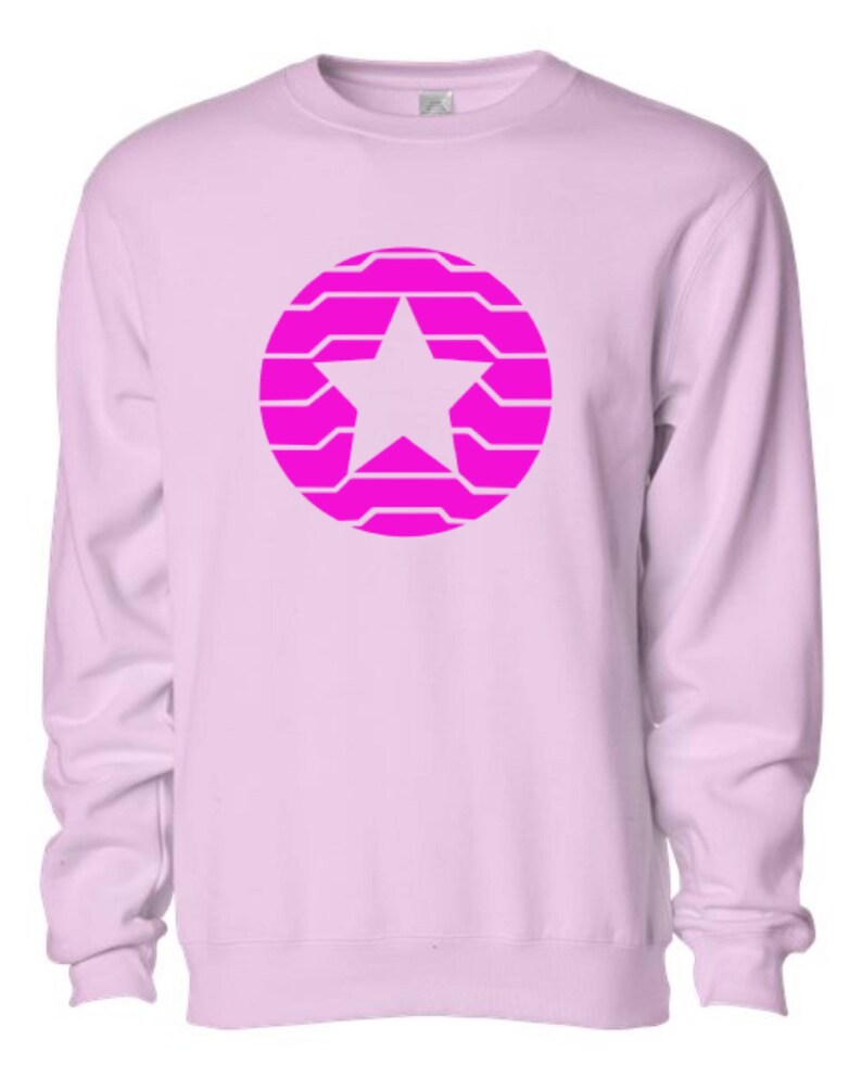 Puede incluir: Sudadera rosa claro con un dise&ntilde;o de estrella rosa brillante dentro de un patr&oacute;n circular. La estrella es blanca. La sudadera tiene mangas largas y cuello redondo.