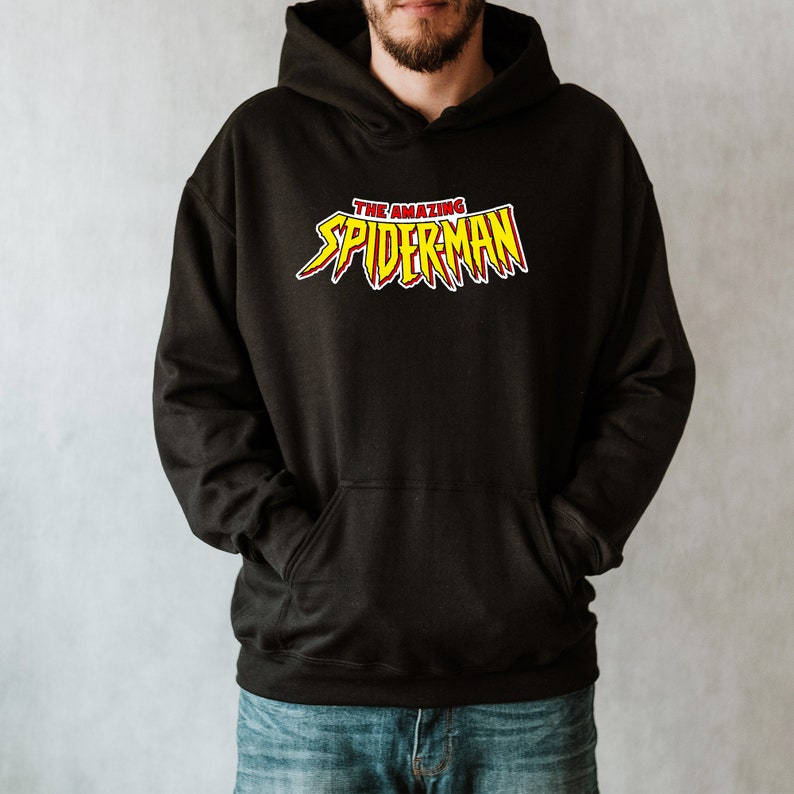 May include: Black hooded sweatshirt with the text "THE AMAZING SPIDER-MAN" in red and yellow lettering. The sweatshirt has a front pocket and a drawstring hood. The design is centered on the chest.