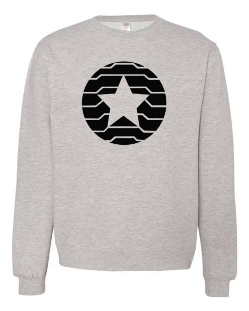 Puede incluir: Sudadera gris claro con un dise&ntilde;o de estrella negra dentro de un patr&oacute;n circular. La estrella est&aacute; centrada y el c&iacute;rculo est&aacute; compuesto por l&iacute;neas horizontales. La sudadera tiene cuello redondo y mangas largas.