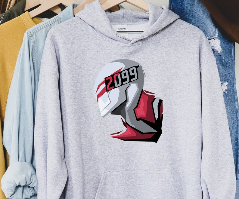 May include: A light gray hoodie featuring a futuristic illustration of a helmet with the number "2099" in red and white. The design is a stylized graphic with red and gray accents. The hoodie is hanging on a wooden hanger.