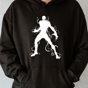 May include: Black hoodie featuring a white graphic of a stylized figure with tendrils. The design is a silhouette of a humanoid form with sharp claws and flowing lines, creating a dynamic and edgy aesthetic. The hoodie has a front pocket and a hood.