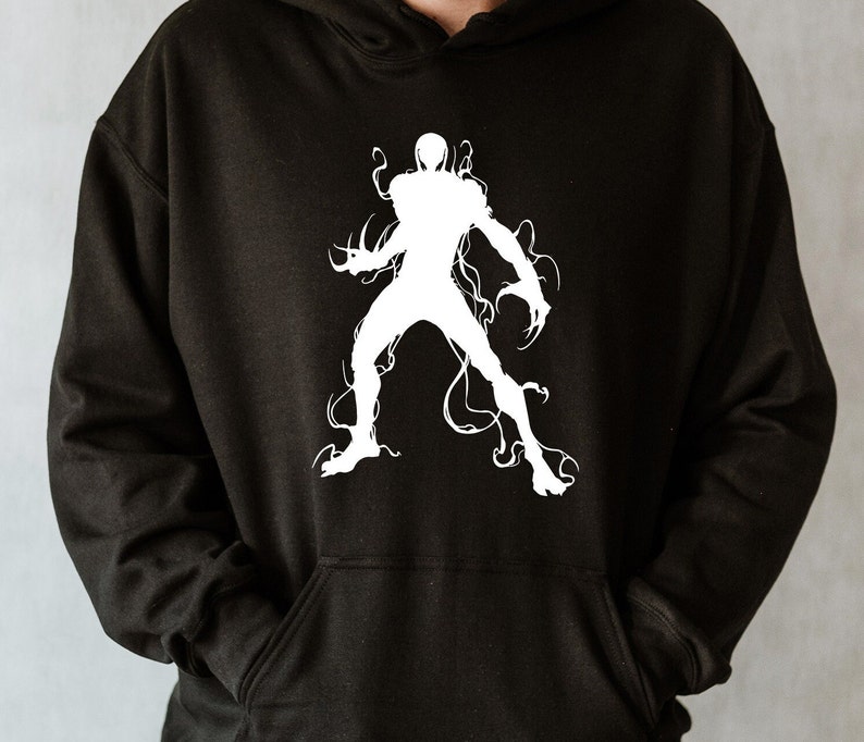 May include: Black hoodie featuring a white graphic of a stylized figure with tendrils. The design is a silhouette of a humanoid form with sharp claws and flowing lines, creating a dynamic and edgy aesthetic. The hoodie has a front pocket and a hood.