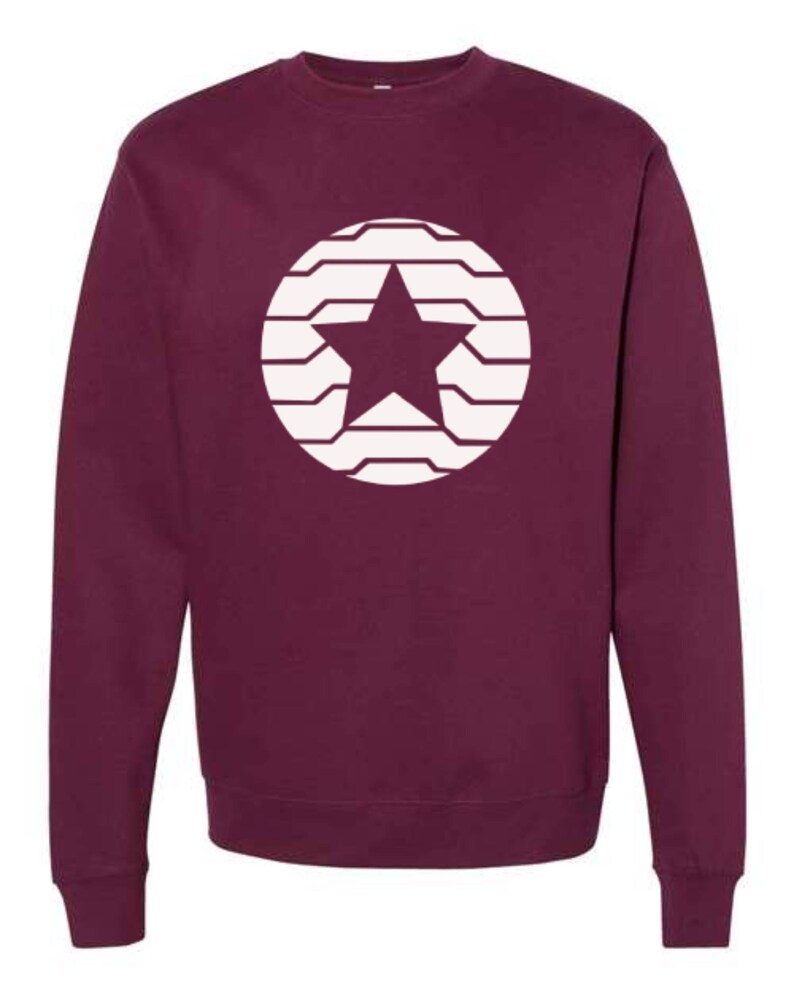 Puede incluir: Sudadera burdeos con un dise&ntilde;o de estrella blanca dentro de un c&iacute;rculo. La estrella est&aacute; centrada y el c&iacute;rculo est&aacute; formado por l&iacute;neas horizontales. La sudadera tiene cuello redondo y mangas largas.