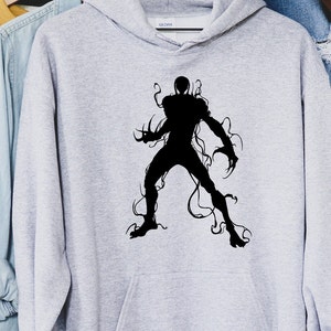 May include: A light gray hoodie featuring a black silhouette of a creature with sharp claws and tendrils. The graphic is centered on the front of the hooded sweatshirt. The hoodie has a drawstring and a front pocket.