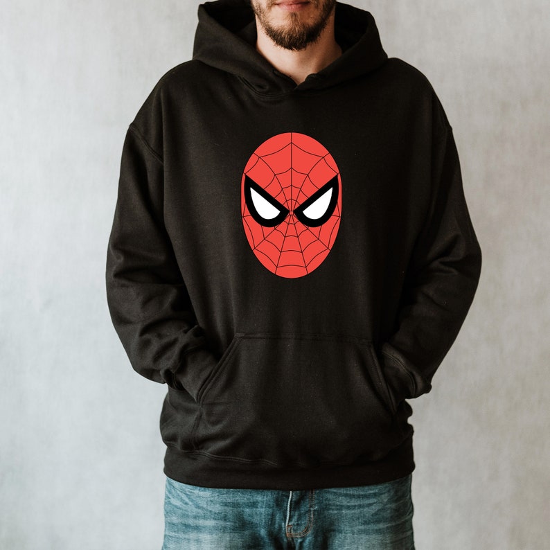 May include: Black hooded sweatshirt featuring a red and black Spider-Man mask design on the front. The graphic is an oval shape with a spiderweb pattern and white eye shapes. The sweatshirt has a front pocket and a drawstring hood.