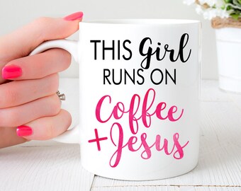 Op de afbeelding: Witte keramische mok met zwarte tekst die "This girl runs on coffee + Jesus" luidt. De tekst "coffee" is roze. Een hand houdt de mok vast.