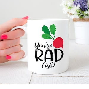May include: White ceramic mug with a black and white graphic of a radish and the text "You're Rad (ish)".