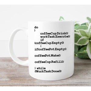 Op de afbeelding: Een witte keramische mok met zwarte computercode-tekst die luidt: do { coffeeCupDrink(); workTaskExecute(); if (coffeeCup.Empty()) { if(coffeePot.Empty()) coffeePot.Make(); coffeeCup.Refill(); } while (!WorkTaskDone());